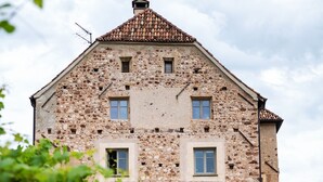 Un edificio in pietra con diverse finestre e un tetto in tegole.