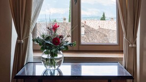 Una stanza con un tavolo, un vaso con fiori e una finestra con tende.