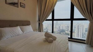 Habitación de hotel con una cama grande, vista del paisaje urbano a través de una ventana y un cartel con la palabra 'Dream'.