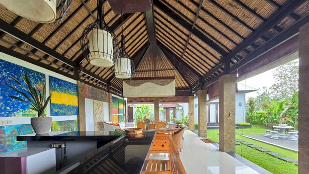 A spacious indoor area with a long wooden bench, a reception desk, and a thatched roof ceiling. - Belvilla Bunga Matahari Ceking Rice Terrace (Taro)