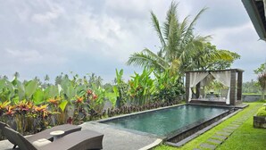 A swimming pool with lounge chairs, a covered seating area, and lush tropical plants. - Belvilla Bunga Matahari Ceking Rice Terrace (Taro)