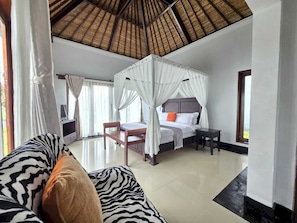 A bedroom with a four-poster bed, a sitting area with a zebra-patterned sofa, and a television.