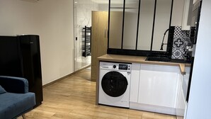 A modern kitchen with a built-in washing machine, a wooden dining table, and a blue sofa.