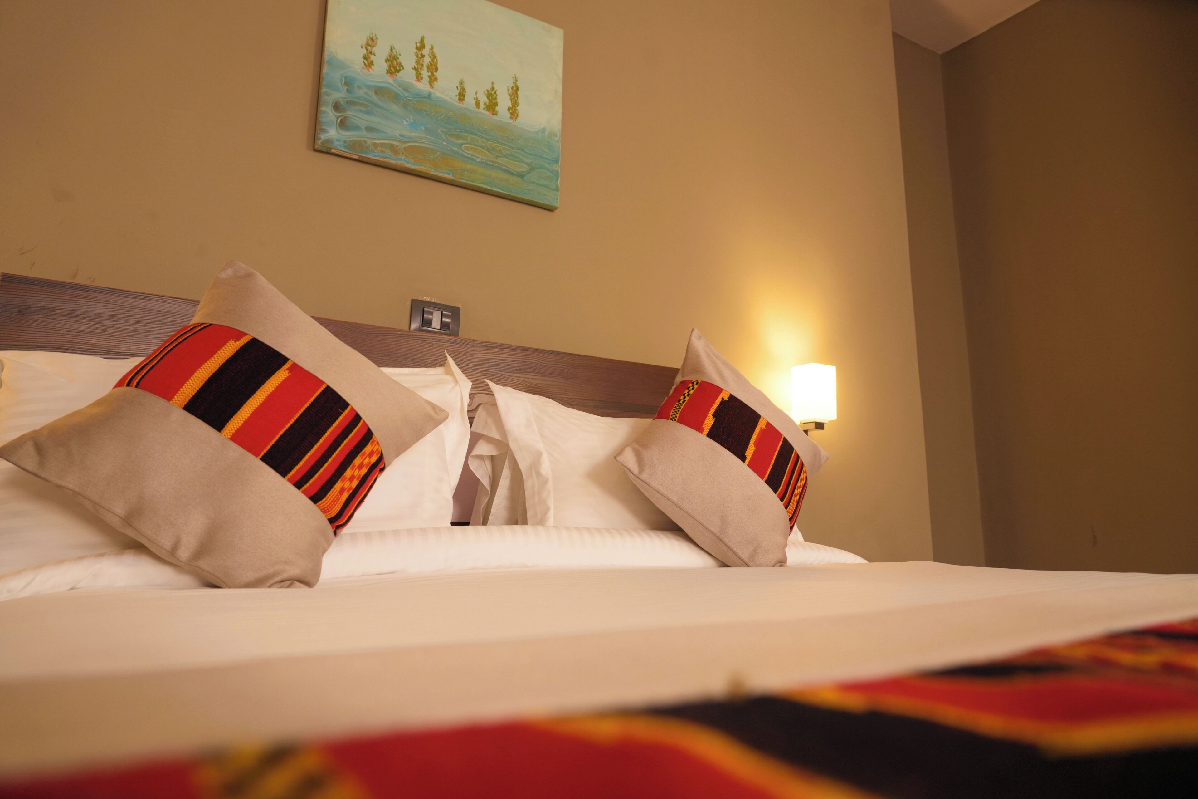A neatly made bed with white linens and two decorative pillows with striped patterns.