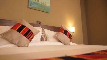 A neatly made bed with white linens and two decorative pillows with striped patterns.