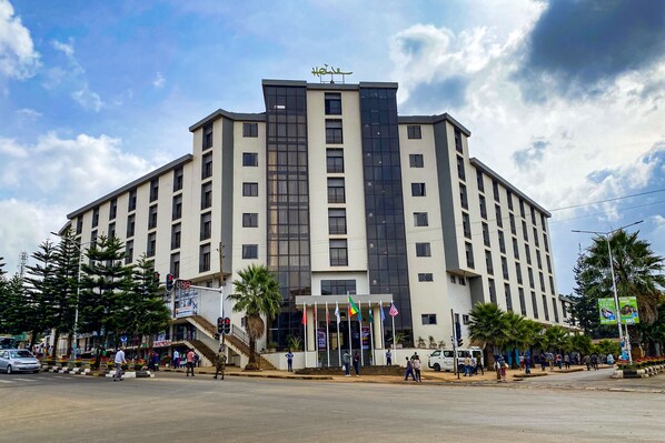 A multi-story hotel with a modern design, featuring a prominent entrance with steps and a flag display. - Haile Hotel Wolaita (Soddu)
