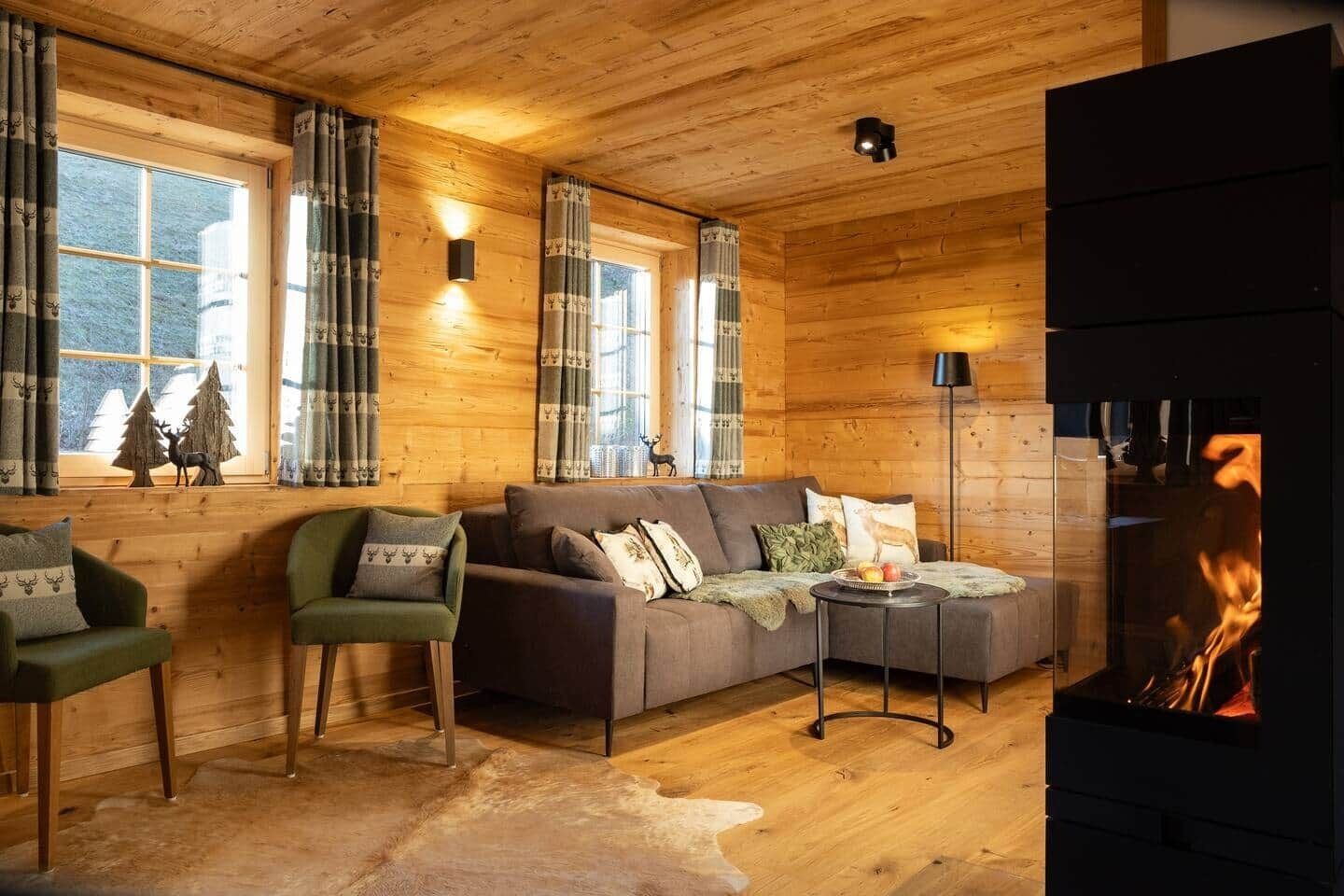 Un intérieur de chalet chaleureux avec une cheminée, des murs en bois et un ensemble de canapés.