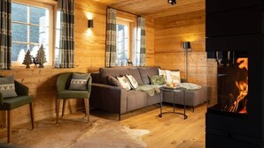 Een gezellig interieur van een chalet met een open haard, houten wanden en een zithoek.