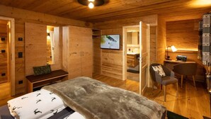 Een knus houten kamer met een bed, een bureau, een stoel en een televisie.