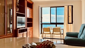 A living room with a large window, a television, and a dining area with a table and chairs. - Bright Sun House with Sea Views (Agüimes)