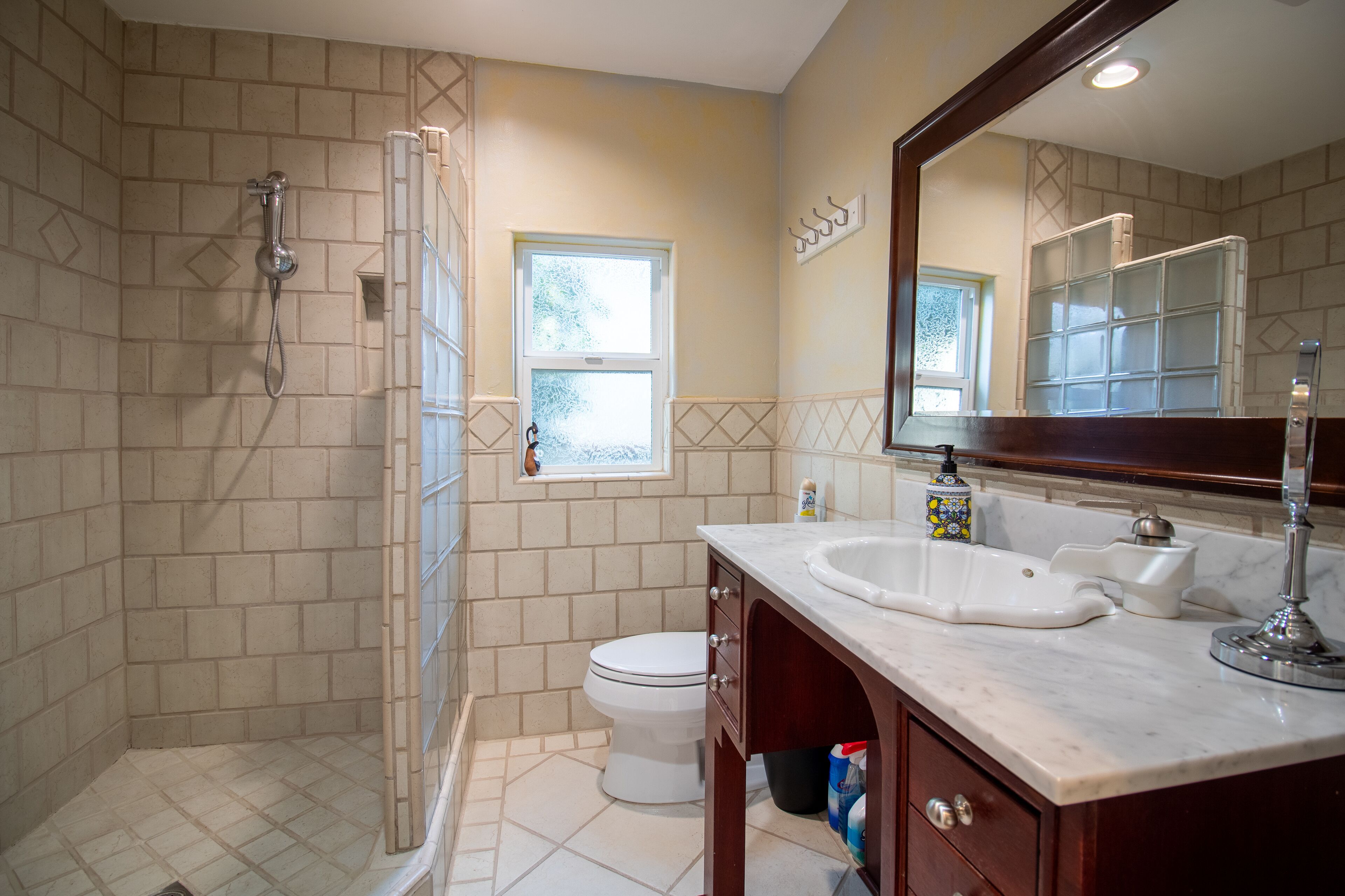 A bathroom with a shower, toilet, and vanity with a sink and mirror.