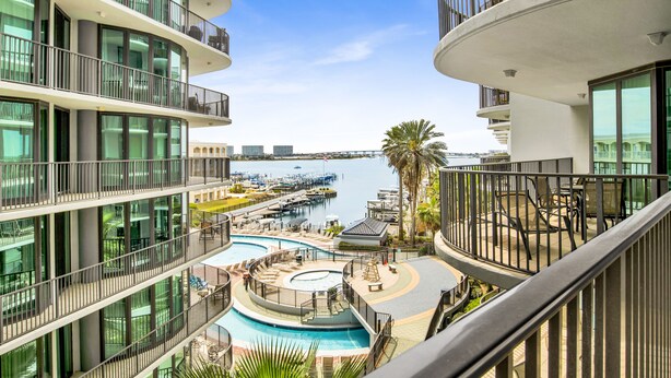 Un hôtel de grande hauteur doté de nombreux balcons donnant sur un port de plaisance et une piscine.