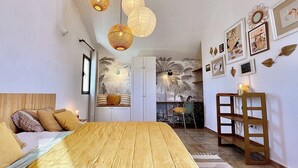 Ein gemütliches Schlafzimmer mit einem hölzernen Bett, hängenden Papierlampen und einer Wand mit gerahmten Kunstwerken.