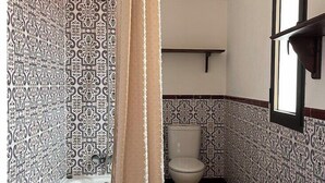 Ein Badezimmer mit gemusterten Fliesen, einer Badewanne, einer Toilette und einem Waschbecken.