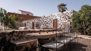 A stone building with a rustic outdoor seating area, including a table and chairs. - Co-Living at Casa Cocolores (La Oliva)
