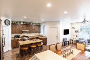 Una cocina amplia con armarios de madera, estufa de acero inoxidable y una barra con taburetes.