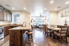 A spacious kitchen with a central island, wooden cabinets, and a dining area with a table and chairs.