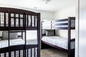 Una habitación con dos literas, una ventana con persianas y una lámpara en el techo.