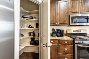 A compact kitchen with built-in appliances, wooden cabinets, and a stainless steel range hood. - The Vintage- Poolside 3 bed 2.5 bath (Washington)