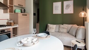 Una cocina moderna con armarios de madera, una mesa de comedor dispuesta con platos y vasos, y una pared verde con obras de arte enmarcadas.