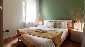 Una cama bien hecha con una bandeja de tazas y platillos, una lámpara de noche y una mesita de noche con lámpara.