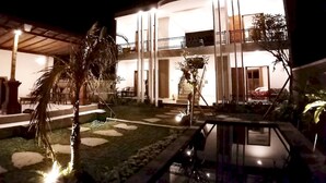 Ein zweistöckiges Gebäude mit Pool, Sitzgelegenheiten im Freien und einem gut beleuchteten Eingang.