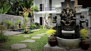Ein Innenhof mit einer Statue, Kübelpflanzen und einem Pool.