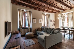 A cozy living room with a wooden ceiling, a sofa, a dining table, and a TV. - First (Como)
