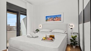A modern hotel room with a large bed, a breakfast tray, a painting, and a balcony view. - Casa Di Natalia (C6QG+8CQ Rhodes, Greece)