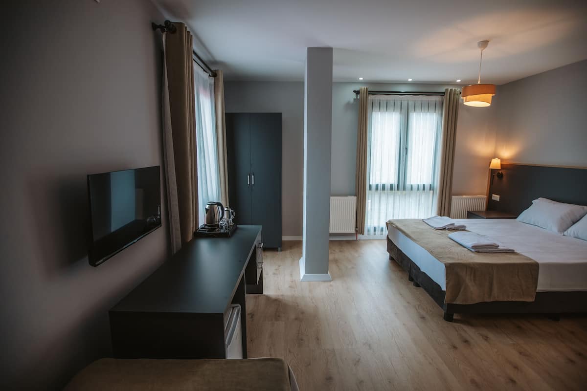 A hotel room with a bed, bedside table, TV, and a desk with a chair.