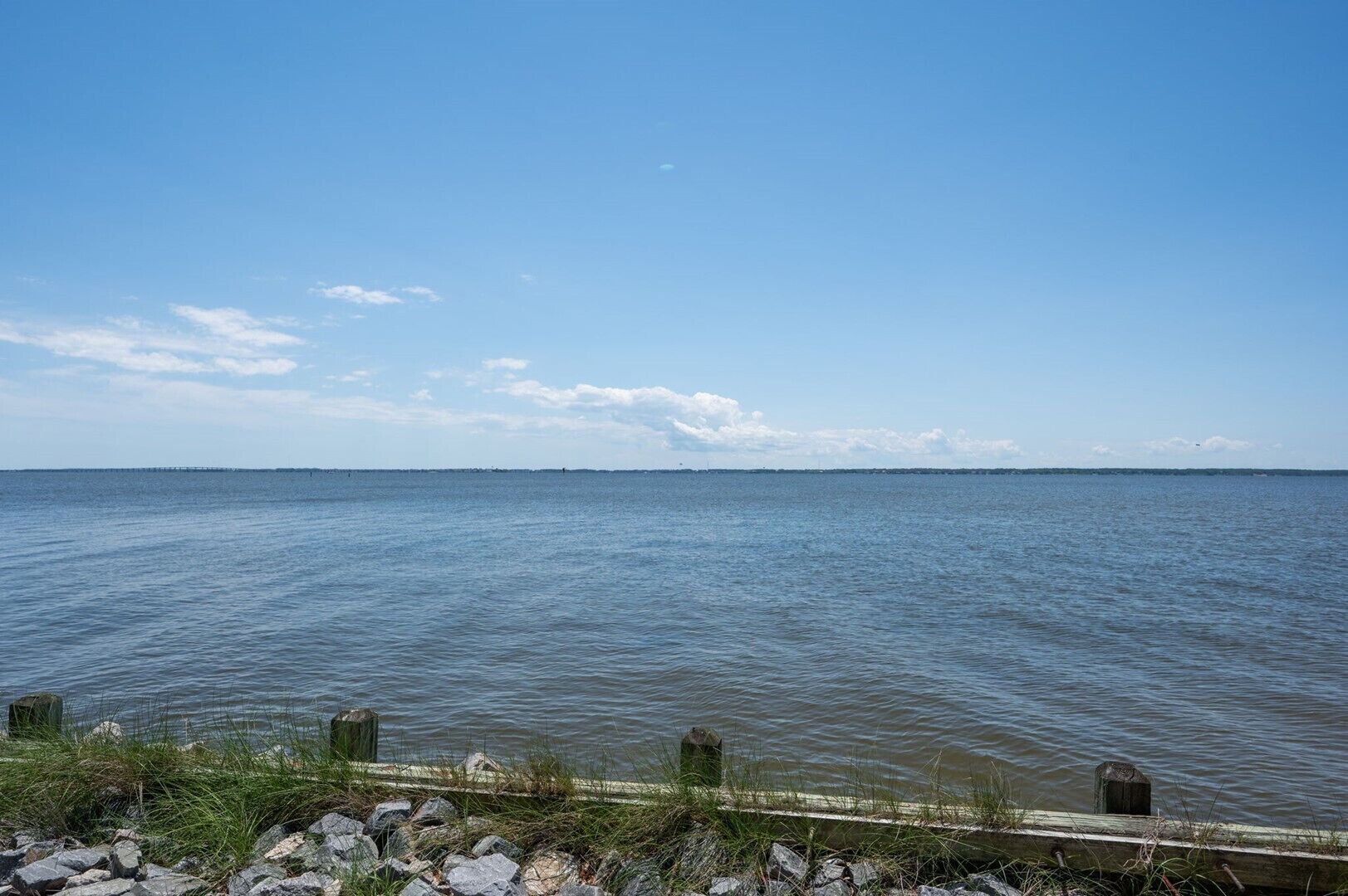 A calm body of water with a clear sky and distant land.