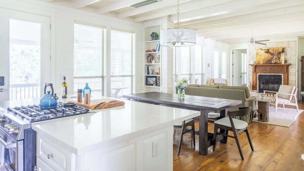 Une cuisine spacieuse avec un grand îlot central, un plancher en bois et une cheminée.