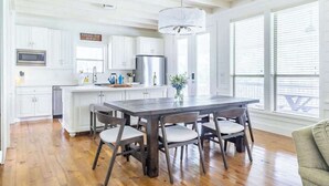 Une cuisine moderne avec des meubles blancs, un îlot central et un coin repas équipé de quatre chaises.