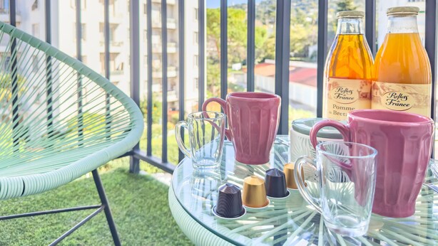 A balcony with a glass table, two bottles of Pomme de P'tit wine, and various colored cups. - Le Palm (Cannes)