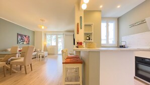 A modern kitchen with a central island, a dining area with a table and chairs, and a living room with a sofa and a coffee table. - Le Palm (Cannes)