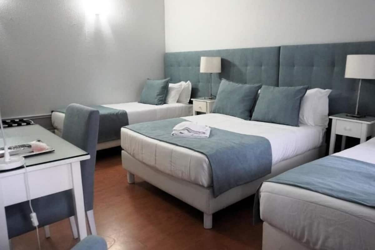 Une chambre d’hôtel avec deux lits, un bureau et des tables de chevet avec des lampes.