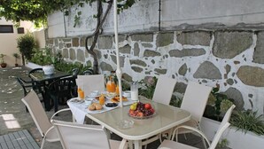 An outdoor dining area with a stone wall, a table set with breakfast, and chairs. - Hotel Senhor de Matosinhos (Matosinhos)