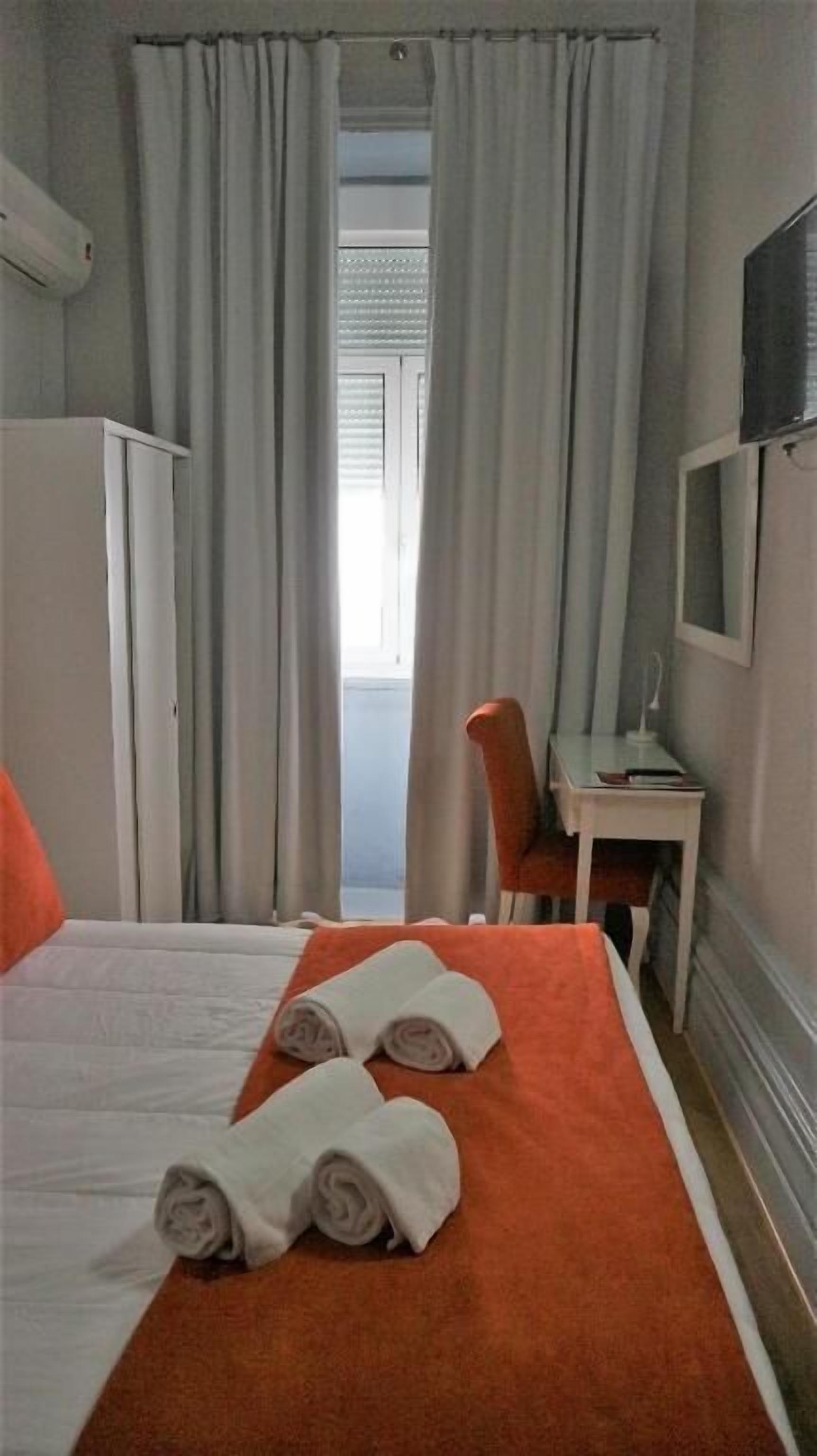 A hotel room with a bed, a desk, a chair, and a TV.