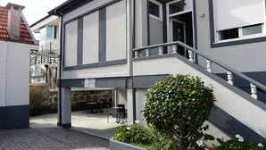 A two-story building with a staircase leading to the upper floor. There is a small outdoor seating area with tables and chairs. - Hotel Senhor de Matosinhos (Matosinhos)
