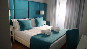 A hotel room with a large bed, teal headboard, white bedding, and a window with curtains. - Hotel Senhor de Matosinhos (Matosinhos)