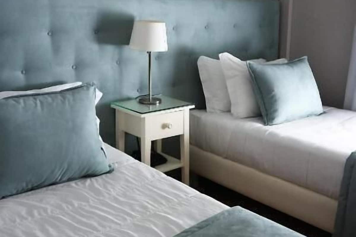 Une chambre d’hôtel avec deux lits, une table de chevet avec une lampe et un appareil de climatisation.
