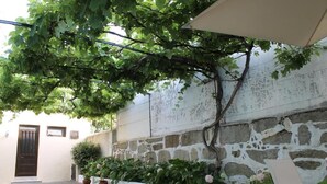 A courtyard with a stone wall, potted plants, and a pergola. - Hotel Senhor de Matosinhos (Matosinhos)