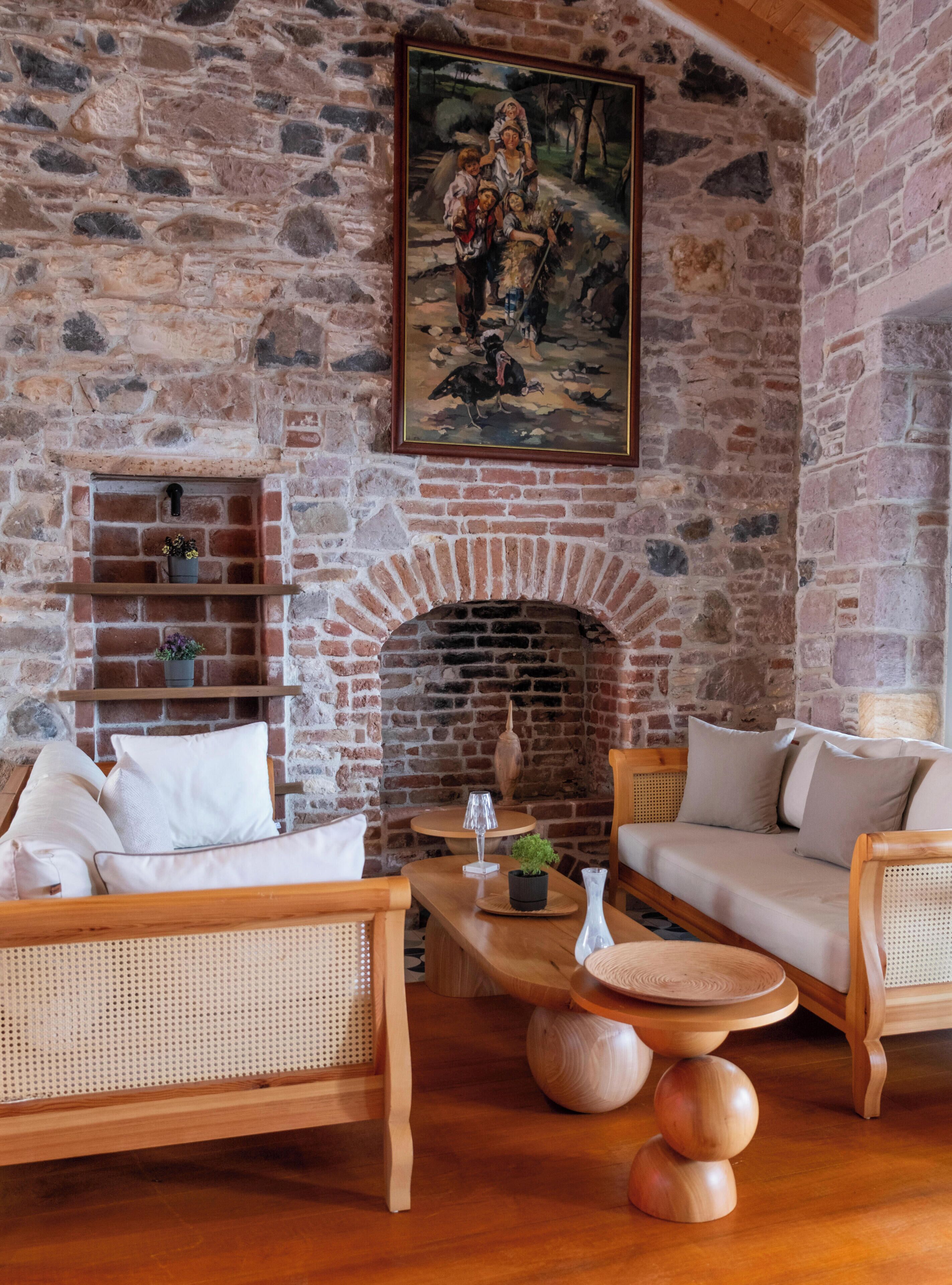 A rustic room with a stone wall, a fireplace, wicker furniture, and a painting.