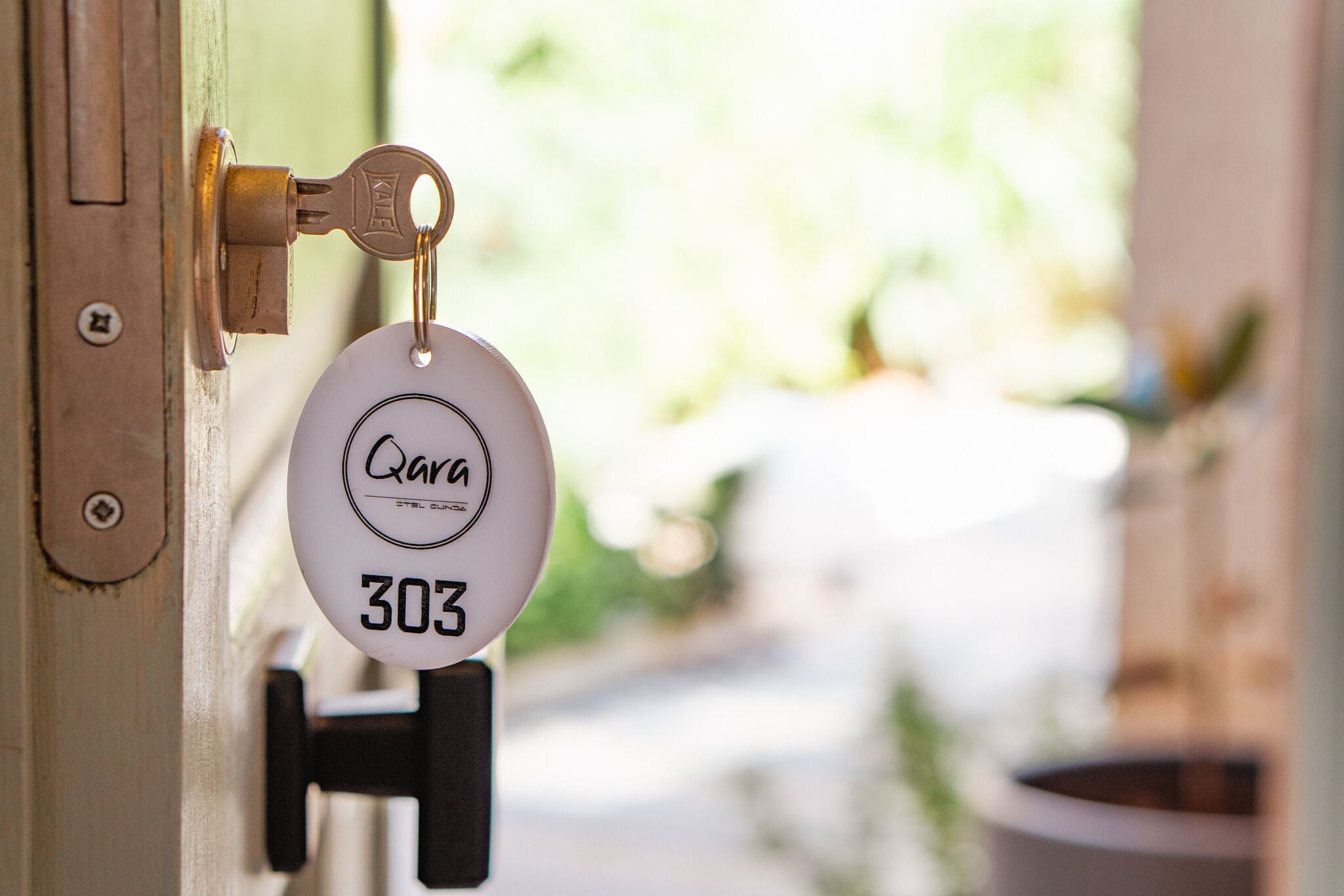 A door lock with a key and a keycard labeled "Qara 303".