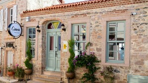 A stone building with a green door, potted plants, and a sign that reads "Qara". - Qara Otel (Ayvalik)