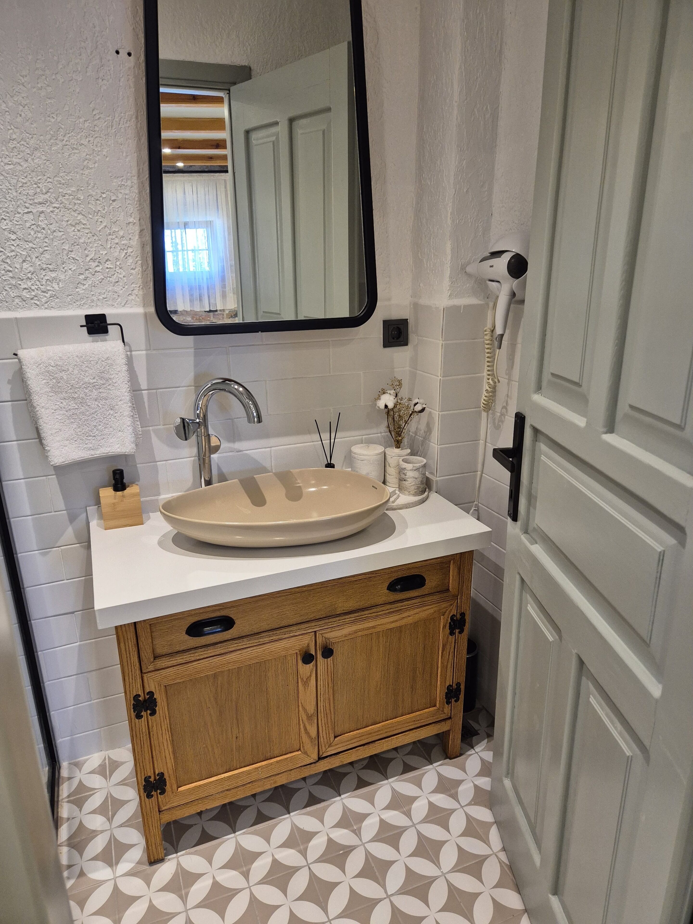 Un baño con tocador de madera, un espejo grande, un lavamanos y un inodoro.