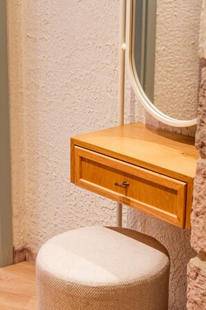 A bathroom with a wooden vanity, a round stool, and a textured wall. - Qara Otel (Ayvalik)