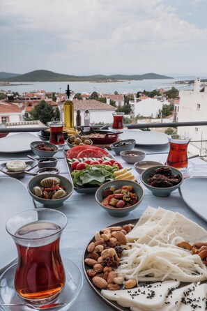 A table with various dishes and a view of a coastal town. - Qara Otel (Ayvalik)