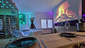 Une cuisine moderne avec un coin repas, une cheminée et un écran de télévision diffusant une image de feu.