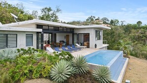 A modern house with a swimming pool, outdoor seating, and lush greenery.